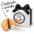 Ciasteczko z wróżbą obok białego pudełeczka z czarną kokardą